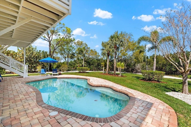 outdoor pool with a patio and a lawn