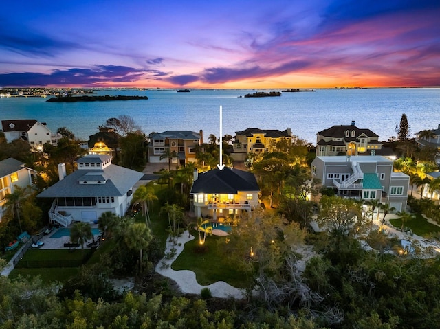 aerial view at dusk featuring a residential view and a water view