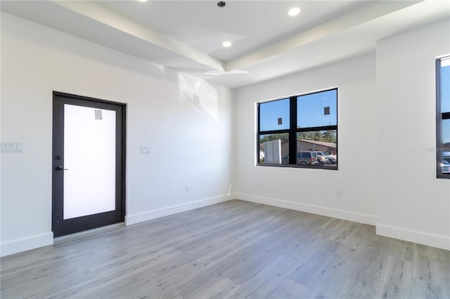 empty room featuring a raised ceiling and light hardwood / wood-style flooring