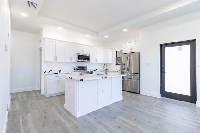 kitchen with a center island with sink, sink, stainless steel appliances, and white cabinetry