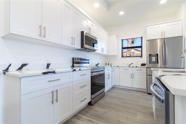 kitchen with light hardwood / wood-style floors, stainless steel appliances, and white cabinetry