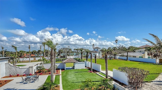 view of property's community featuring a patio, a lawn, and fence