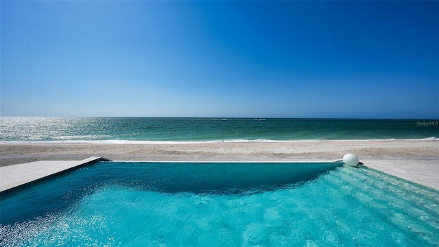 view of pool featuring a water view and a beach view