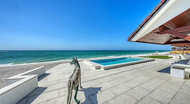 view of swimming pool with a view of the beach, a water view, and a patio