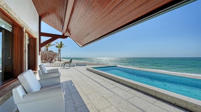 balcony featuring a patio area, a water view, a beach view, and an outdoor hangout area