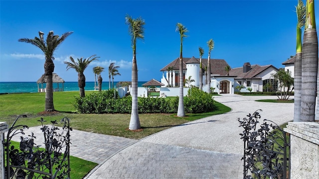 surrounding community featuring decorative driveway, a water view, and a lawn