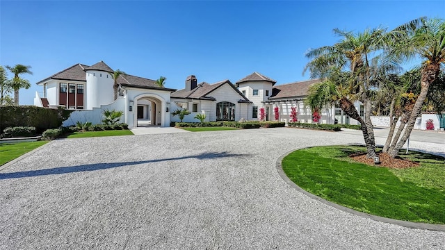 french provincial home featuring curved driveway, a front lawn, and stucco siding