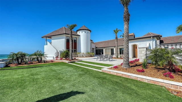 back of property featuring a patio area, a yard, and stucco siding