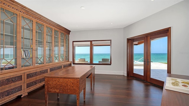 dining room featuring french doors, dark wood-type flooring, a water view, and baseboards