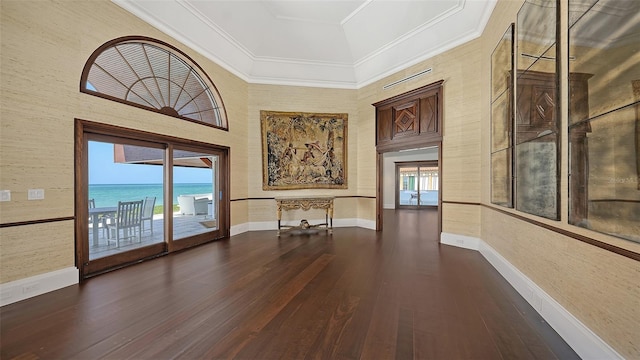 interior space with dark wood-type flooring, ornamental molding, a towering ceiling, and baseboards