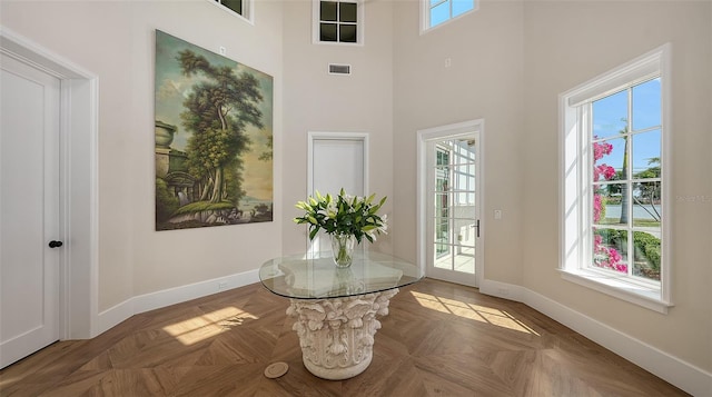 interior space with a towering ceiling, visible vents, and baseboards