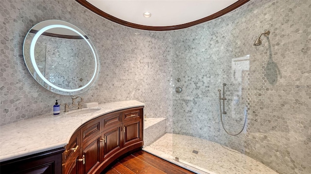 bathroom with a walk in shower, wood finished floors, vanity, and crown molding