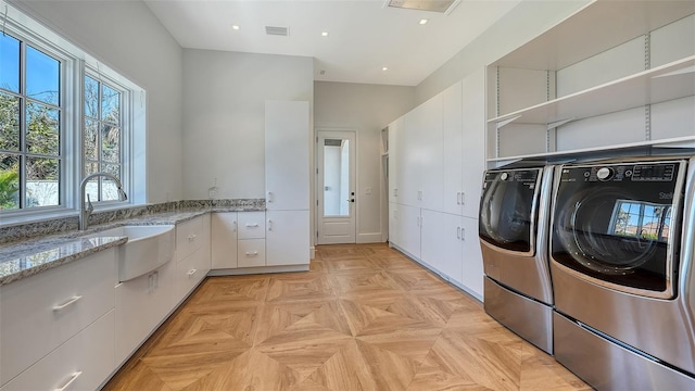 laundry room featuring independent washer and dryer, cabinet space, a sink, and visible vents