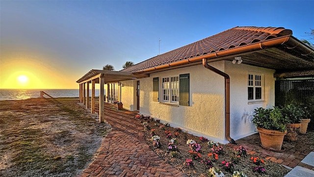 view of home's exterior with a tile roof, a water view, and stucco siding