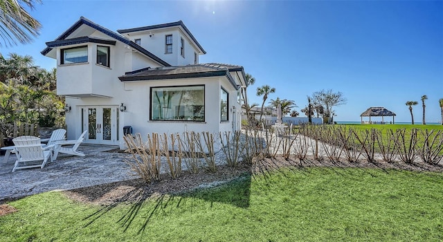 view of front facade featuring a patio, french doors, a front lawn, and stucco siding