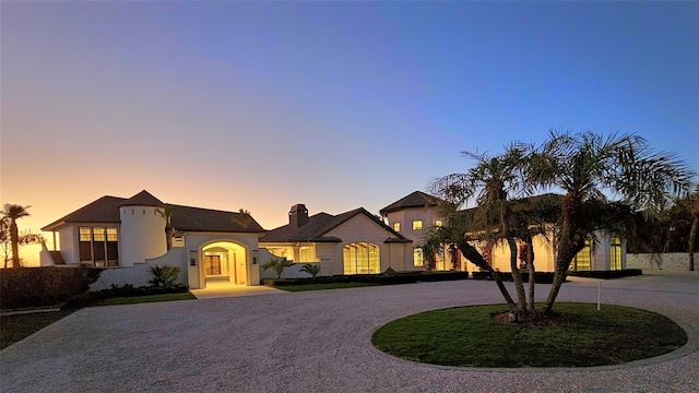 view of front of property featuring curved driveway and stucco siding