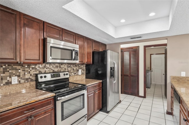 13112 Groveland St, Spring Hill, FL 34609 - kitchen with light tile patterned flooring, stainless steel appliances, visible vents, backsplash, and a tray ceiling