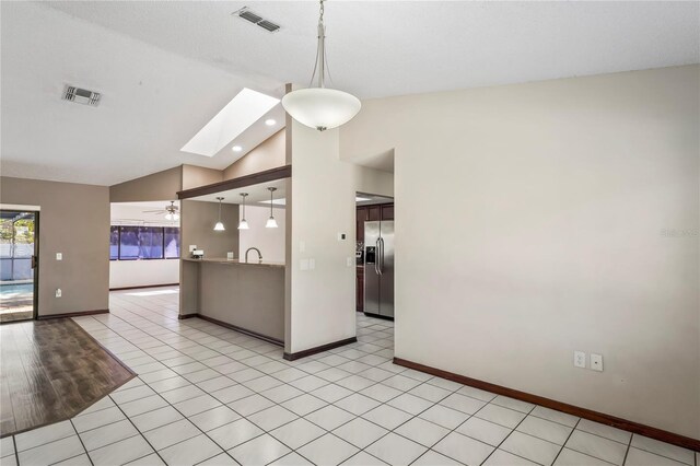13112 Groveland St, Spring Hill, FL 34609 - kitchen with decorative light fixtures, vaulted ceiling with skylight, stainless steel fridge, and visible vents