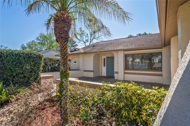 13112 Groveland St, Spring Hill, FL 34609 - doorway to property featuring roof with shingles and stucco siding