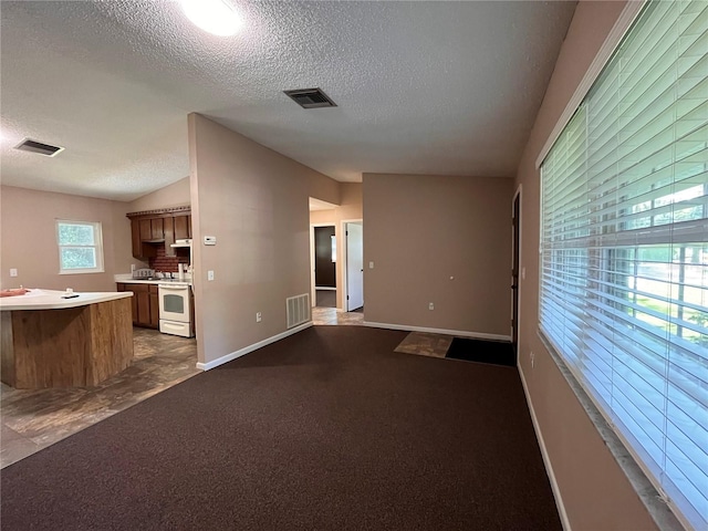 unfurnished living room featuring vaulted ceiling, a textured ceiling, and visible vents