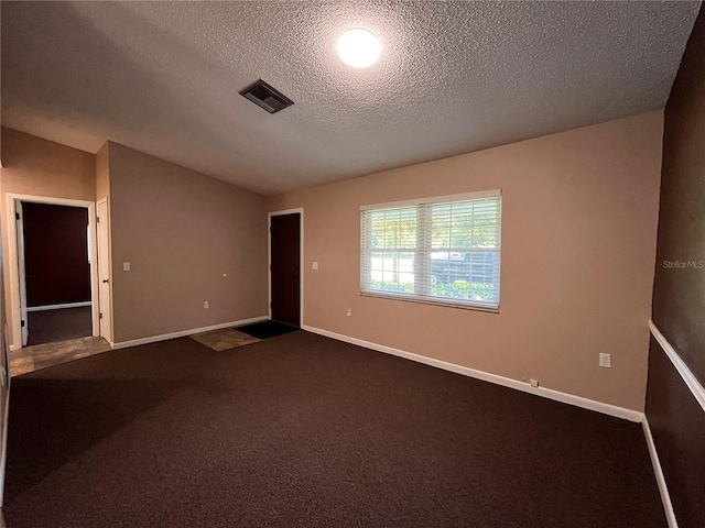 unfurnished room with dark colored carpet, visible vents, vaulted ceiling, and baseboards