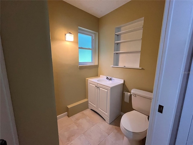 bathroom featuring built in features, baseboards, toilet, tile patterned flooring, and vanity