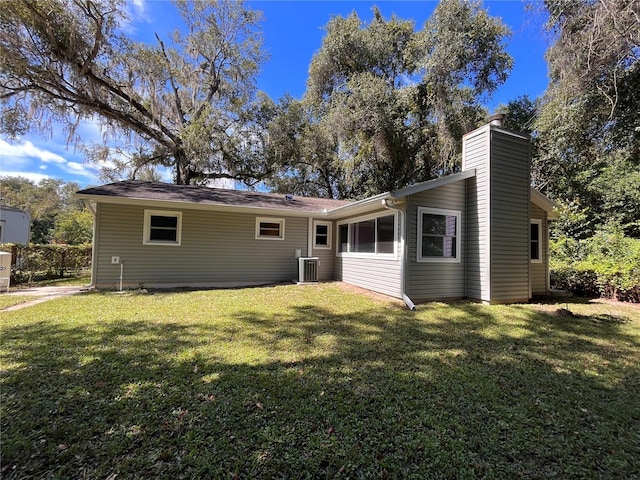 rear view of house featuring a lawn, a chimney, and cooling unit