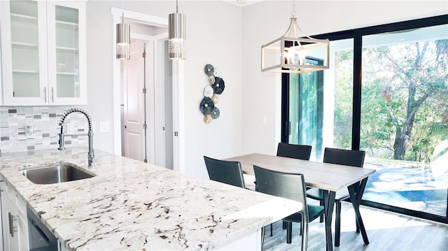 kitchen with pendant lighting, a sink, glass insert cabinets, and white cabinets