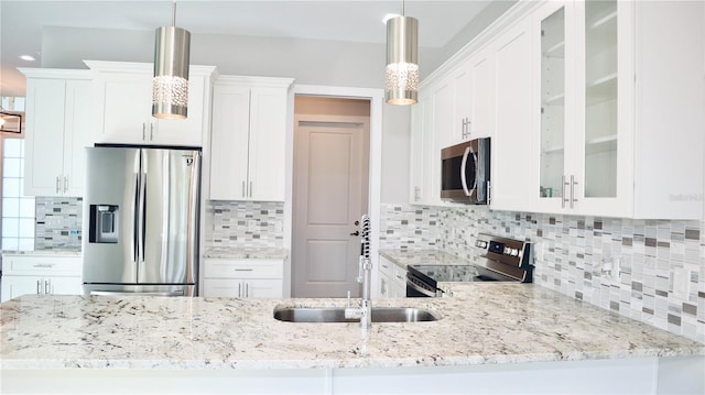 kitchen with glass insert cabinets, appliances with stainless steel finishes, white cabinets, and decorative light fixtures