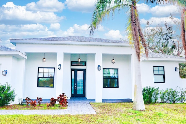 exterior space featuring a front yard, roof with shingles, and stucco siding