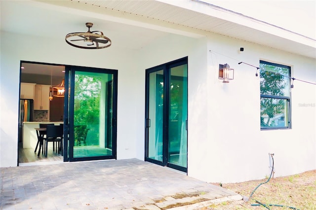 property entrance with a patio area, a ceiling fan, and stucco siding