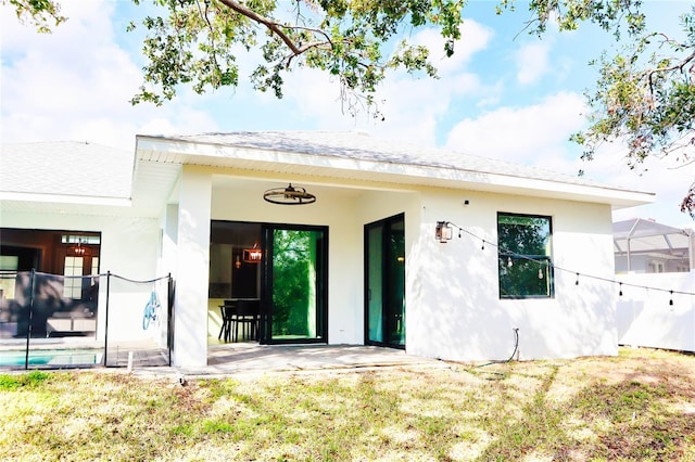 view of exterior entry with a patio area, stucco siding, a ceiling fan, and a yard