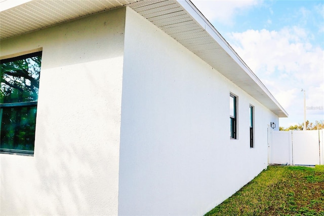 view of side of home featuring fence and stucco siding