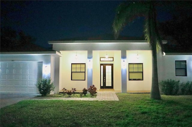 view of front of property with an attached garage, stucco siding, and a front yard