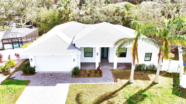 view of front of home with a garage, a front yard, a lanai, and decorative driveway