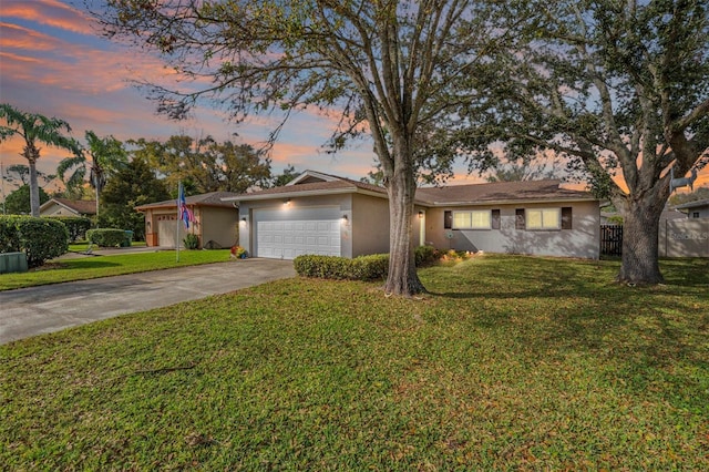 ranch-style house featuring driveway, a lawn, an attached garage, and stucco siding