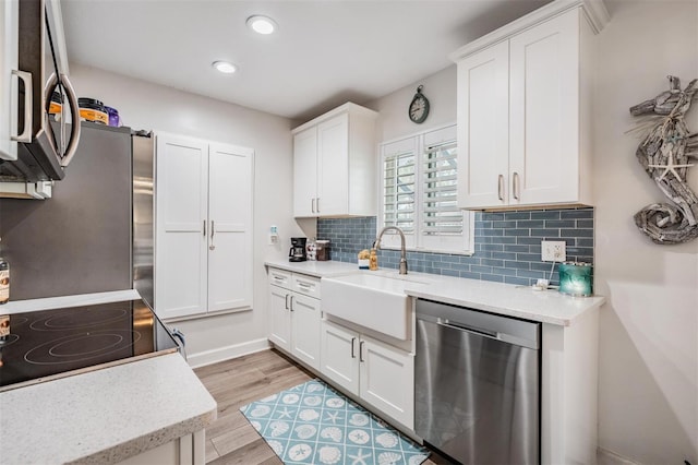 kitchen featuring stainless steel appliances, backsplash, a sink, and white cabinets