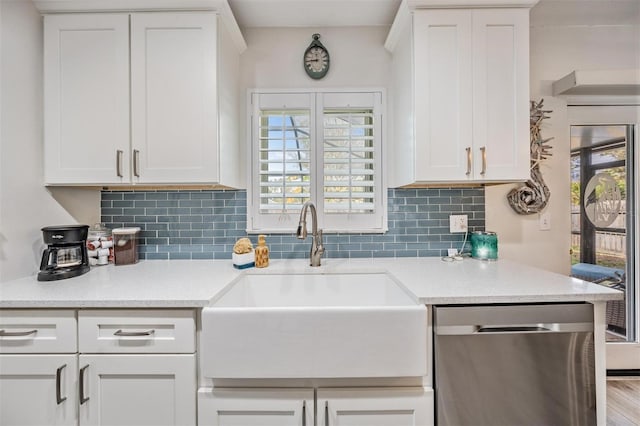 kitchen featuring stainless steel dishwasher, a sink, and white cabinets