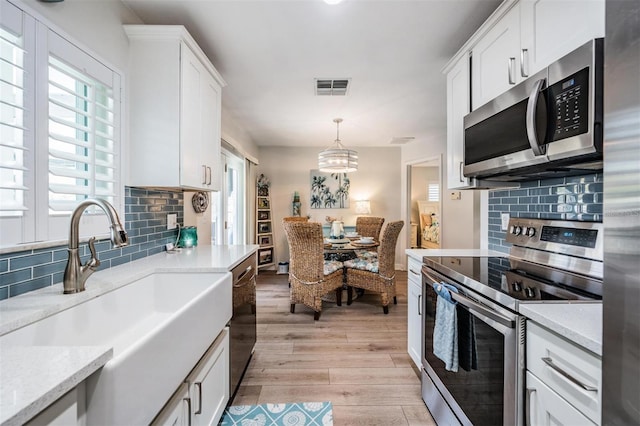 kitchen with stainless steel appliances, white cabinets, visible vents, and a sink