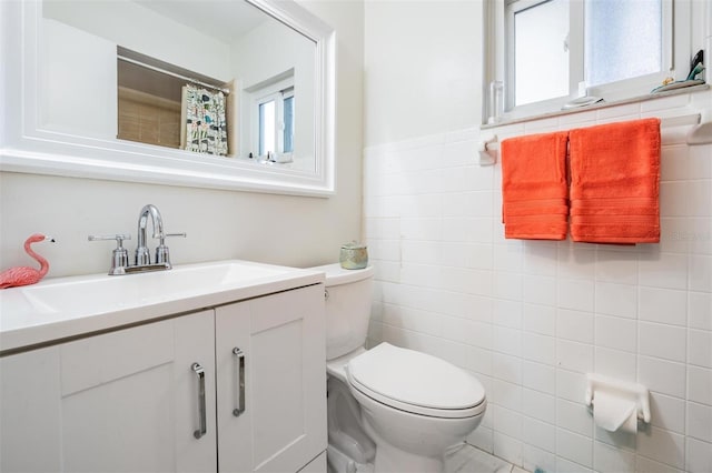 bathroom with toilet, tile walls, and vanity