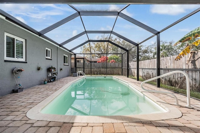 view of swimming pool with glass enclosure, a fenced backyard, a patio area, and a fenced in pool