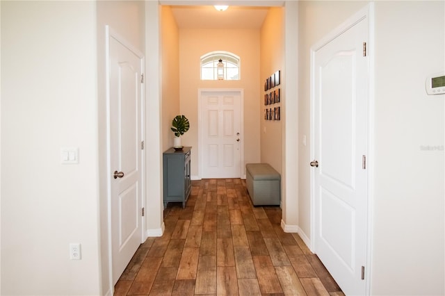 corridor featuring dark wood-style flooring and baseboards