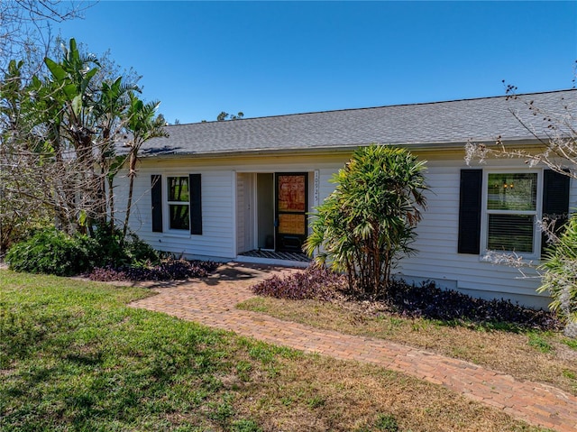 ranch-style home featuring roof with shingles and a front yard