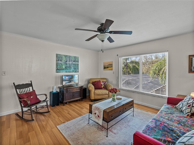 living area featuring ceiling fan, light wood-style flooring, and baseboards