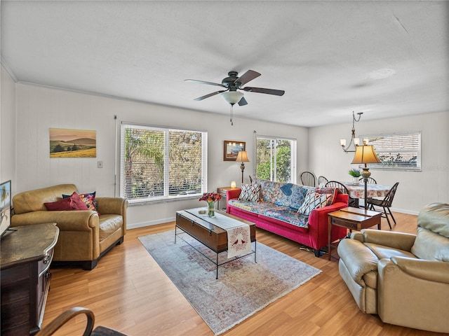 living area featuring ceiling fan with notable chandelier, light wood finished floors, and baseboards