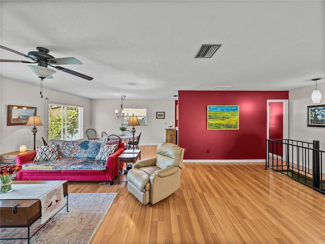 living room with light wood finished floors, baseboards, visible vents, and a notable chandelier