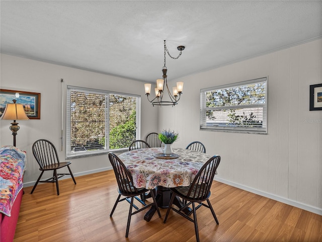 dining area featuring baseboards, a textured ceiling, an inviting chandelier, and light wood-style floors