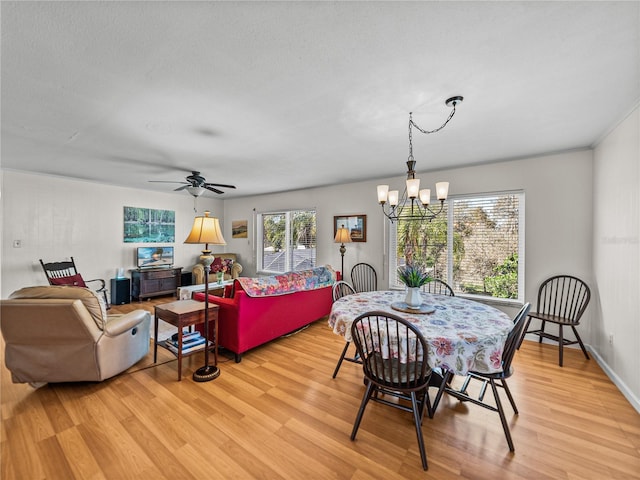 dining space featuring light wood-type flooring and ceiling fan with notable chandelier