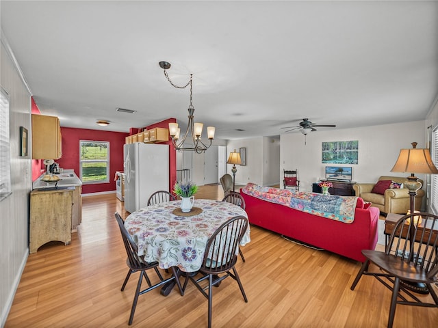 dining room featuring baseboards, visible vents, light wood finished floors, and ceiling fan with notable chandelier