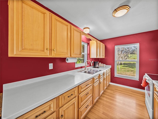 kitchen featuring light wood finished floors, white electric range, light countertops, a sink, and baseboards